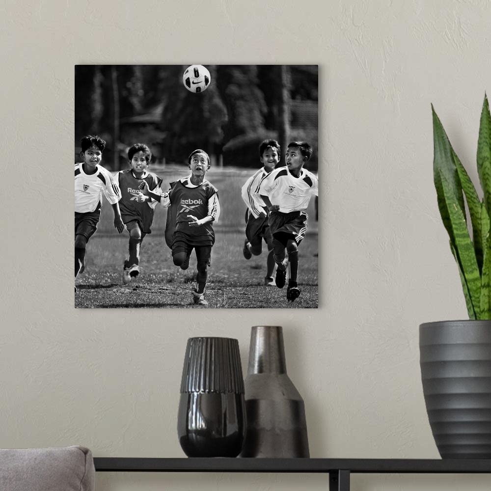 A modern room featuring A group of young boys playing soccer in a field, with the ball in the air.