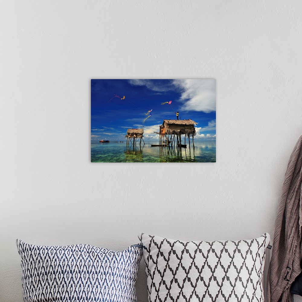 A bohemian room featuring Kites flying over a group of houses on stilts in the ocean, Sabah, Malaysia.
