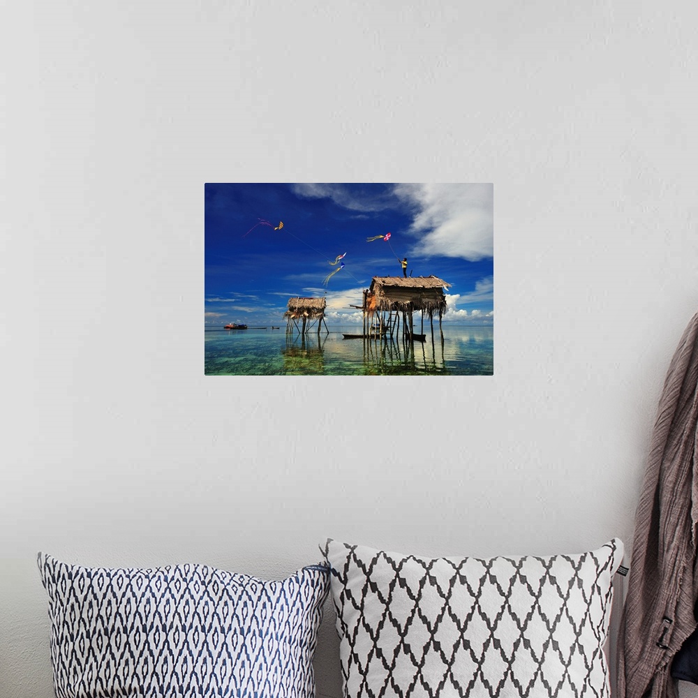 A bohemian room featuring Kites flying over a group of houses on stilts in the ocean, Sabah, Malaysia.