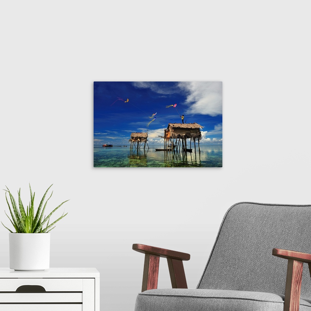A modern room featuring Kites flying over a group of houses on stilts in the ocean, Sabah, Malaysia.