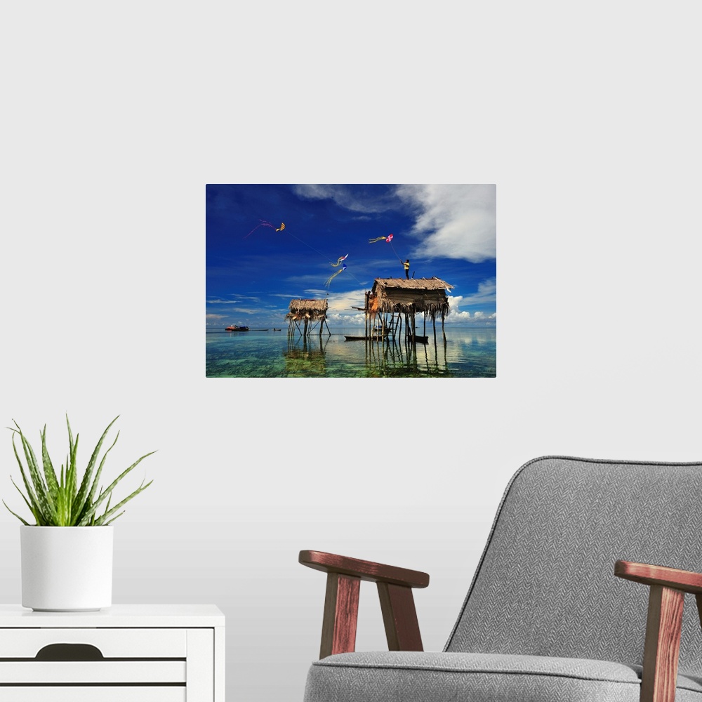 A modern room featuring Kites flying over a group of houses on stilts in the ocean, Sabah, Malaysia.