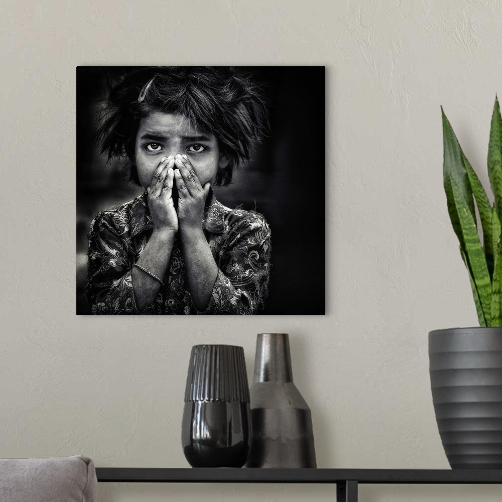A modern room featuring Black and white portrait of a young girl holding her hands to her face.