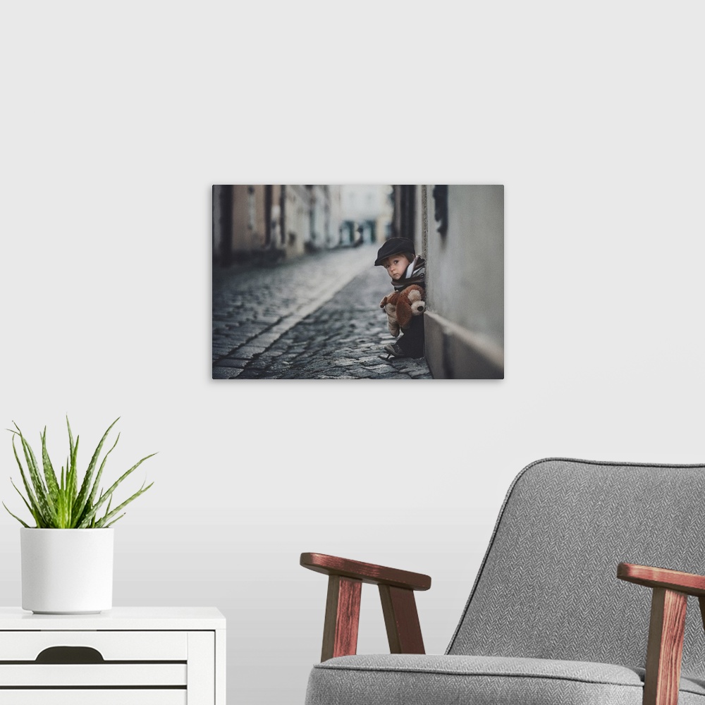 A modern room featuring A portrait of a little boy sitting on a doorstep on a cobblestone road.