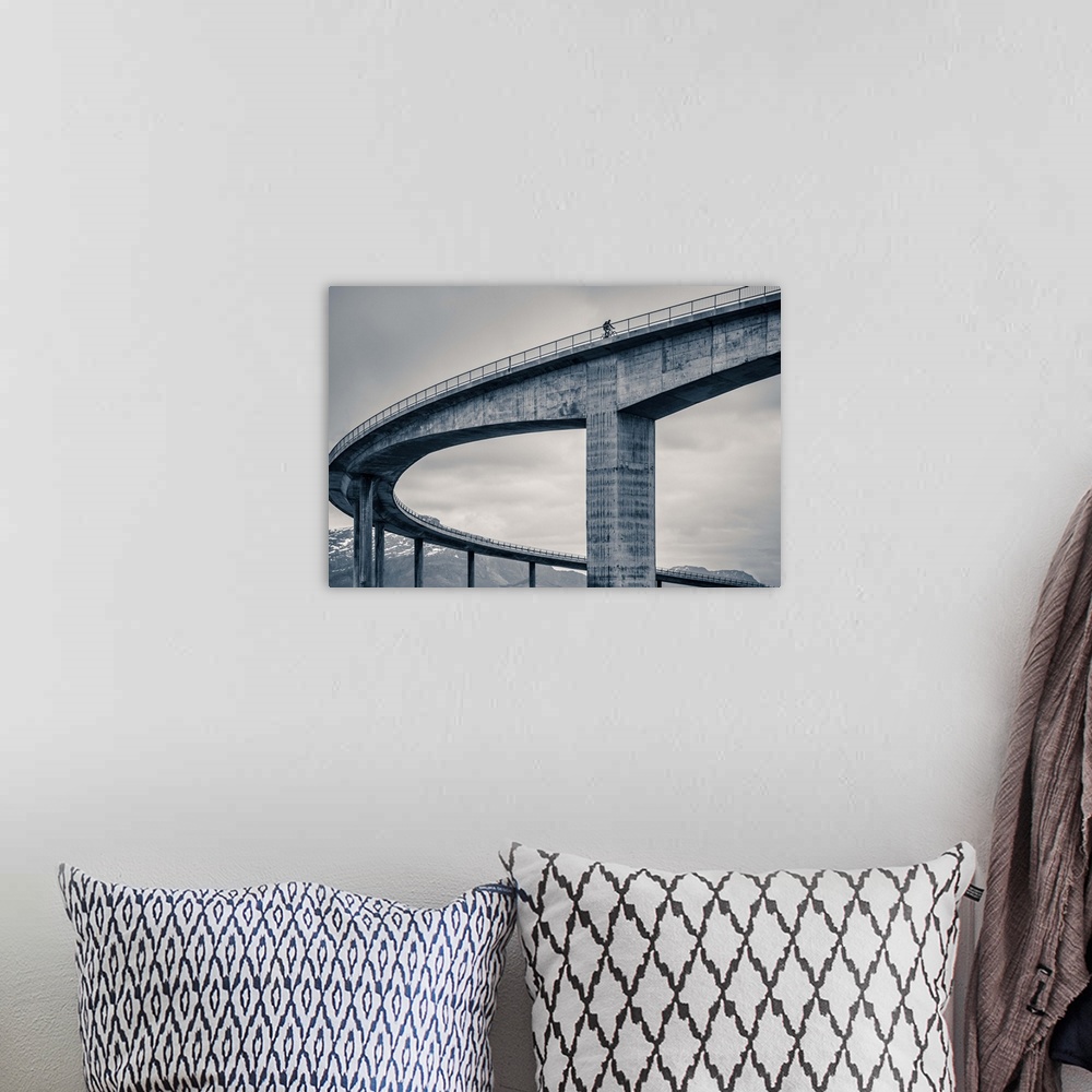 A bohemian room featuring A biker riding across the top of a tall concrete bridge, Norway.