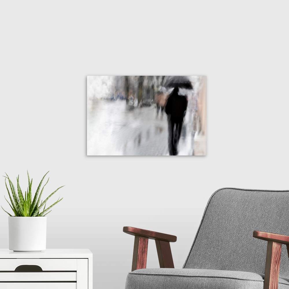 A modern room featuring Blurred image of a figure with an umbrella walking in the rain.