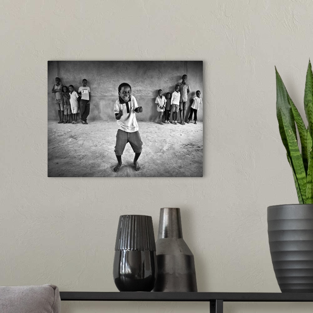 A modern room featuring Portrait of a little boy dancing and have a laugh while other children watch him.