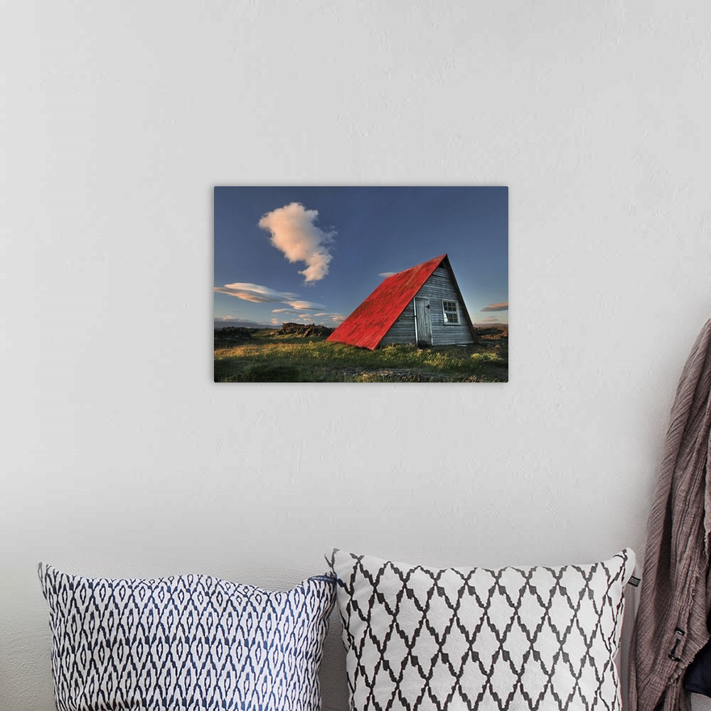 A bohemian room featuring a wooden hut in Iceland with a bright red roof, seen at sunset.