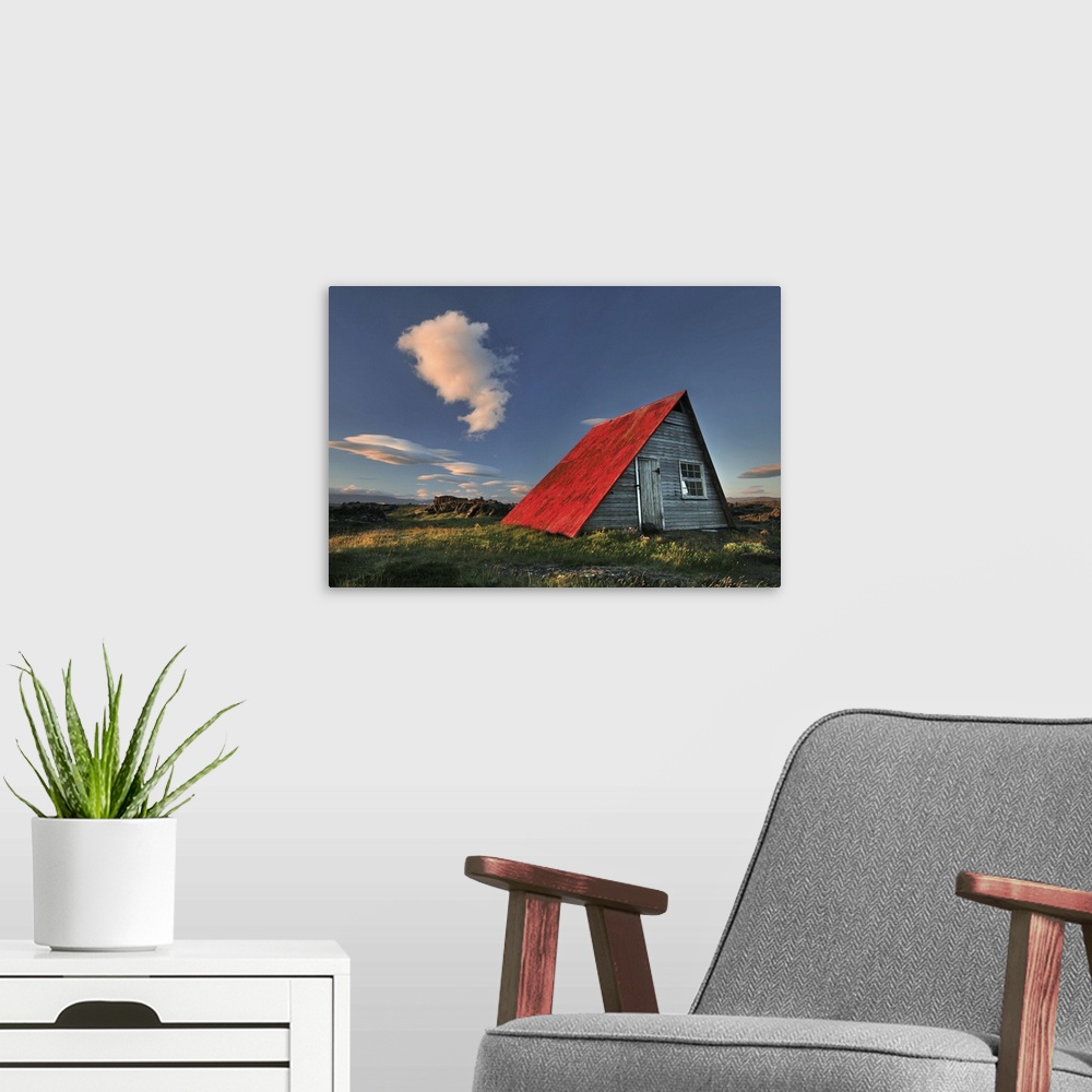A modern room featuring a wooden hut in Iceland with a bright red roof, seen at sunset.
