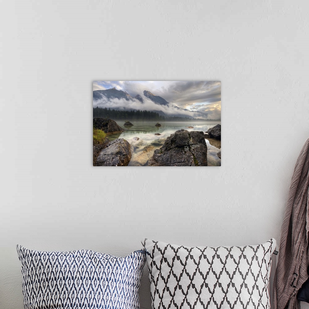 A bohemian room featuring Rocks on the shore of a lake below mountains obscured by clouds, Germany.