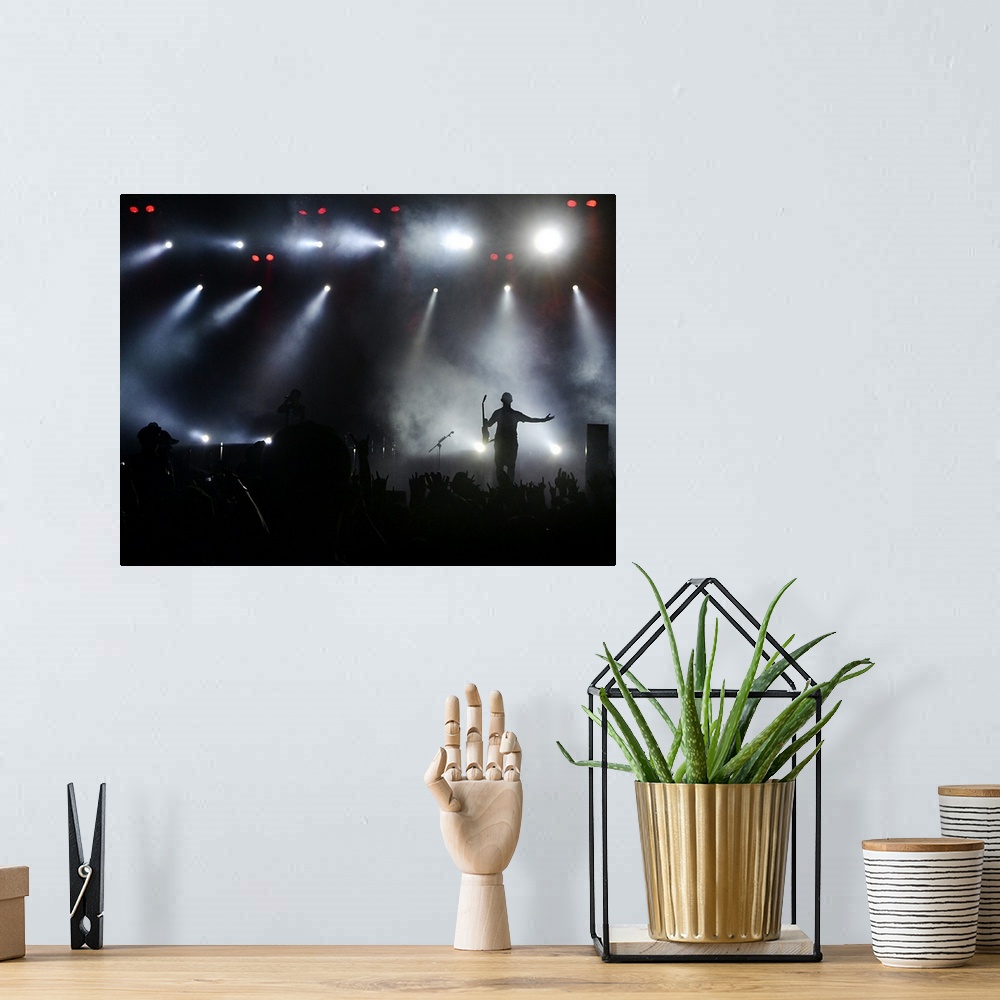 A bohemian room featuring A musician greets his fans on stage under the bright lights during a concert.
