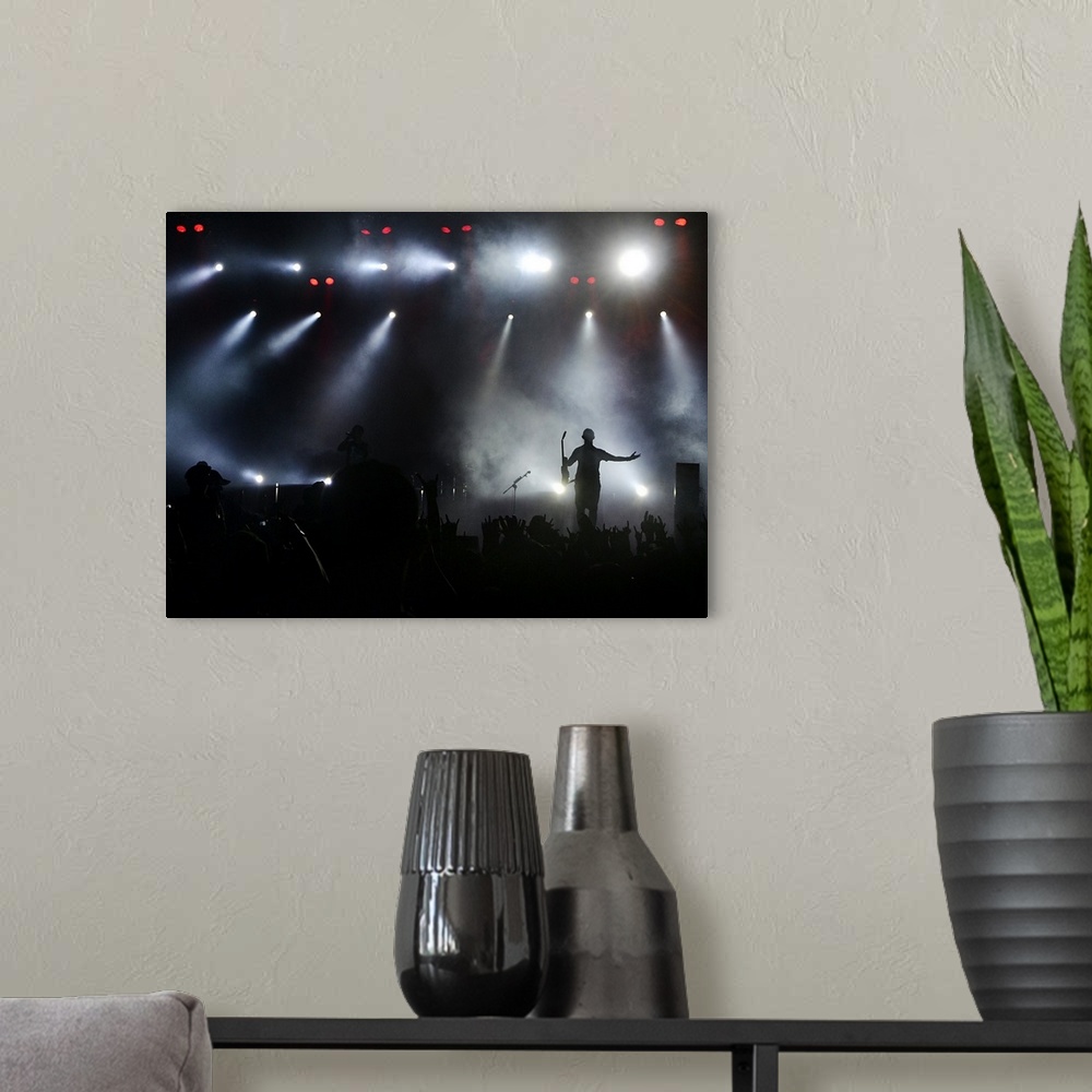 A modern room featuring A musician greets his fans on stage under the bright lights during a concert.