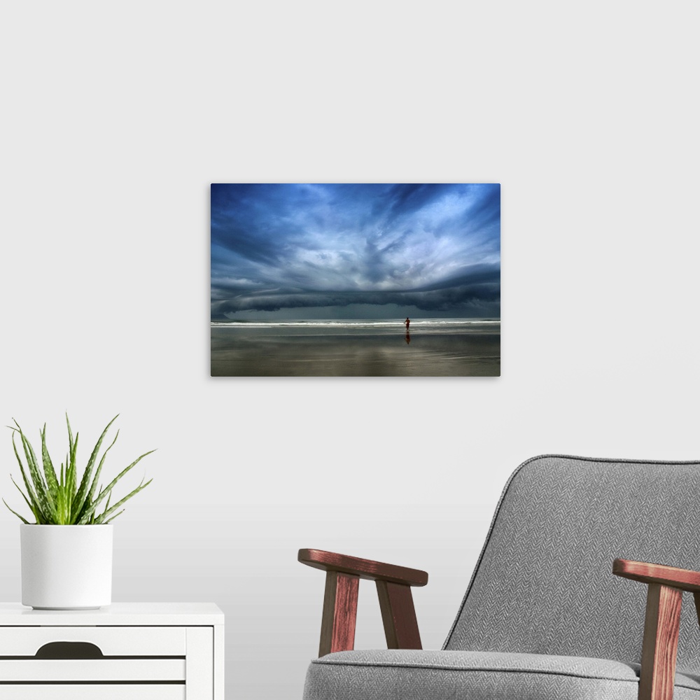 A modern room featuring Adventurous surfer heads into the water, undeterred by the approaching stormclouds.