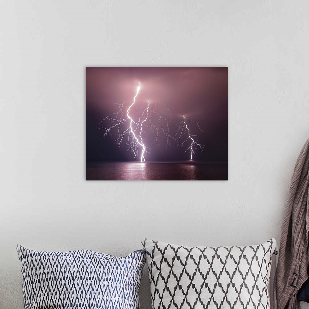 A bohemian room featuring Dramatic image of three lightning bolts striking the ocean at night.