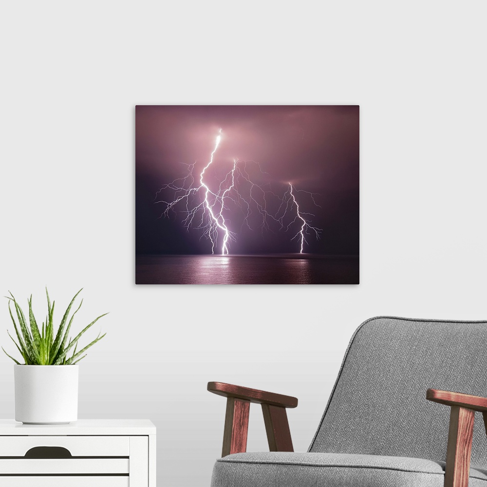 A modern room featuring Dramatic image of three lightning bolts striking the ocean at night.