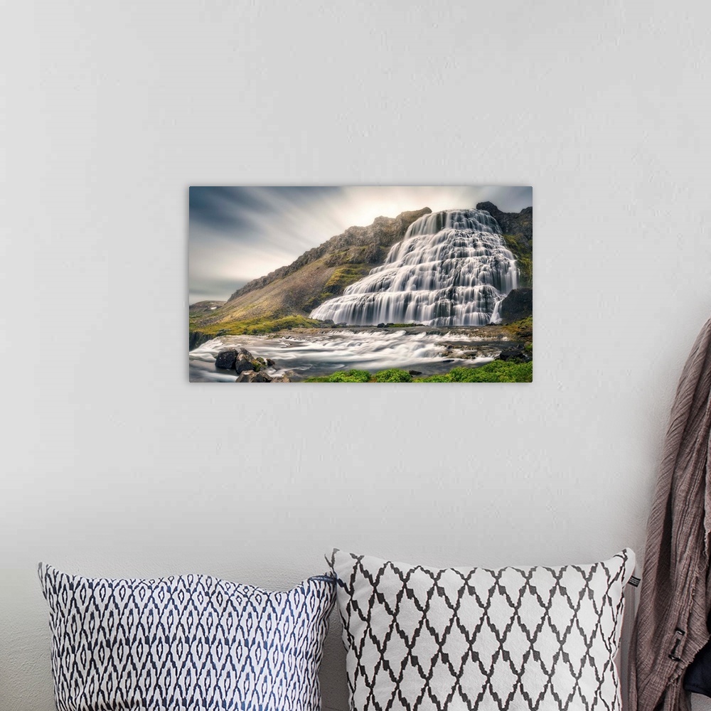 A bohemian room featuring A giant Icelandic waterfall with motion blurred clouds above.