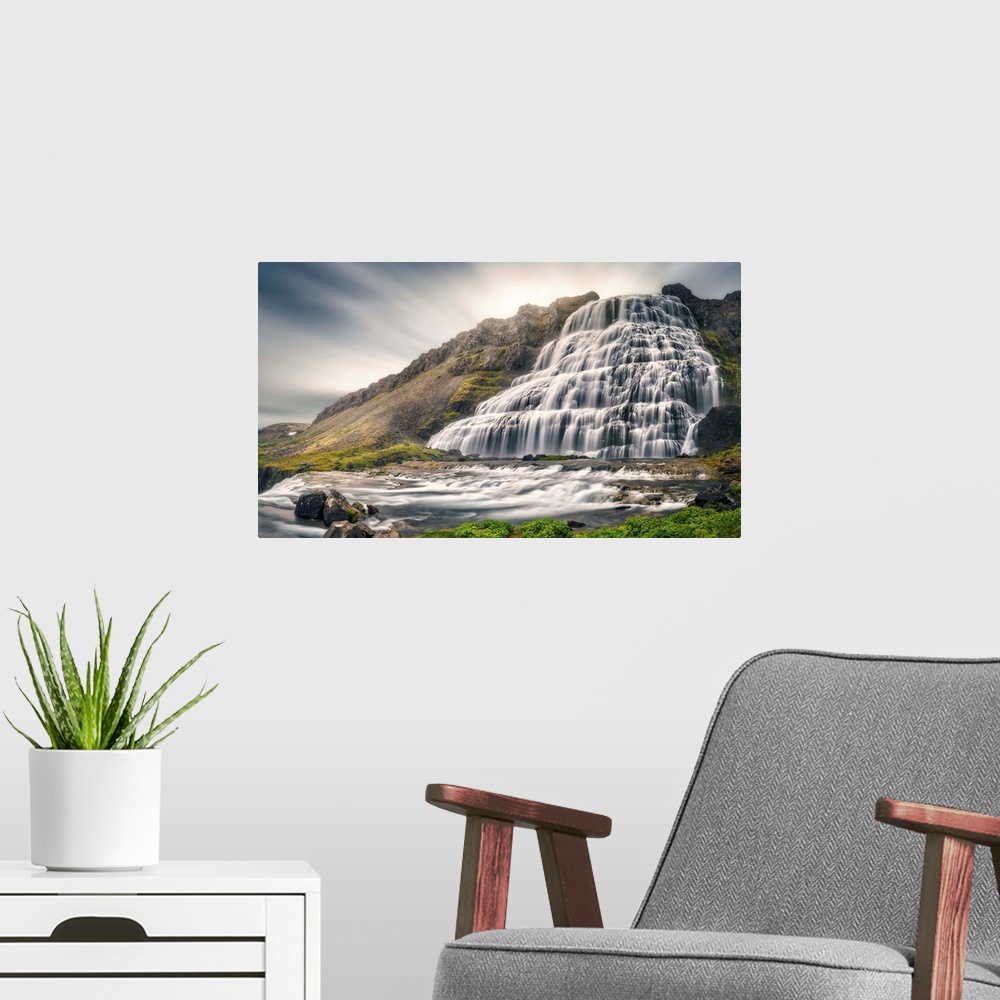 A modern room featuring A giant Icelandic waterfall with motion blurred clouds above.