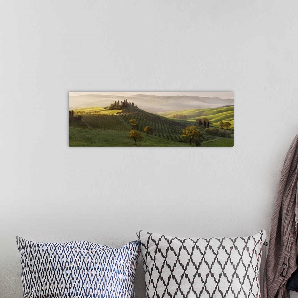 A bohemian room featuring Tuscan countryside scene in early morning light with fog rolling in over the valley, Italy.