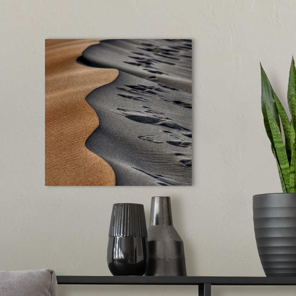 A modern room featuring Two opposing sides of a sand dune, one smooth and orange, the other grey and full of footprints.