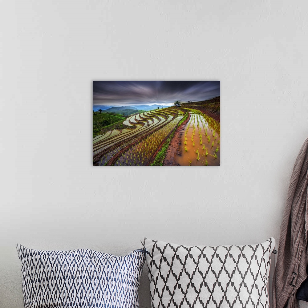 A bohemian room featuring Dramatic scene of terraced rice fields under a sky of intense dark clouds.