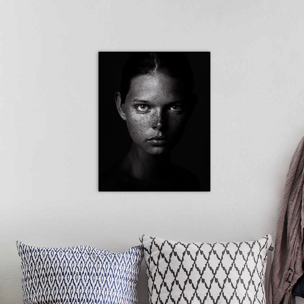 A bohemian room featuring Black and white portrait of a young woman with a freckled visage and a stern expression.