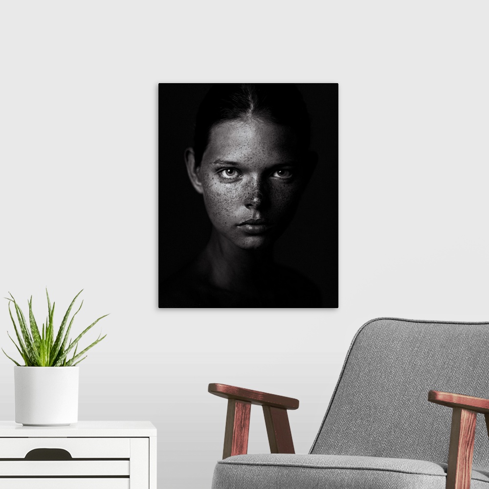 A modern room featuring Black and white portrait of a young woman with a freckled visage and a stern expression.