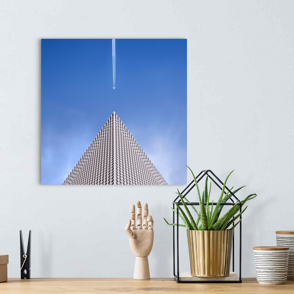 A bohemian room featuring Looking up at the top of a skyscraper with an airplane leaving a vapor trail behind him.