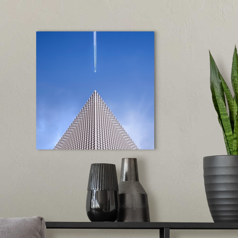 A modern room featuring Looking up at the top of a skyscraper with an airplane leaving a vapor trail behind him.