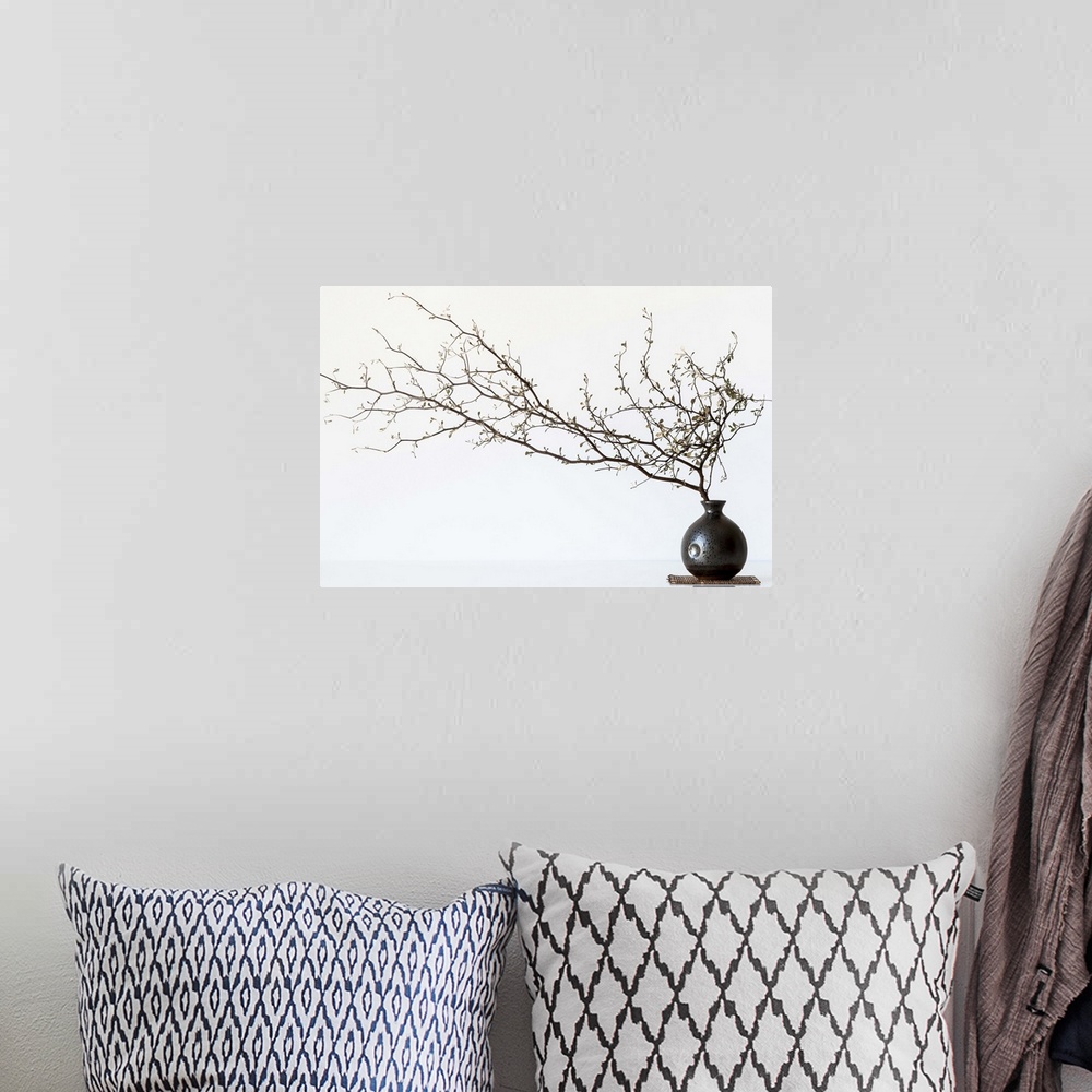 A bohemian room featuring Still life photography of a branch with several small flowers in a round vase.