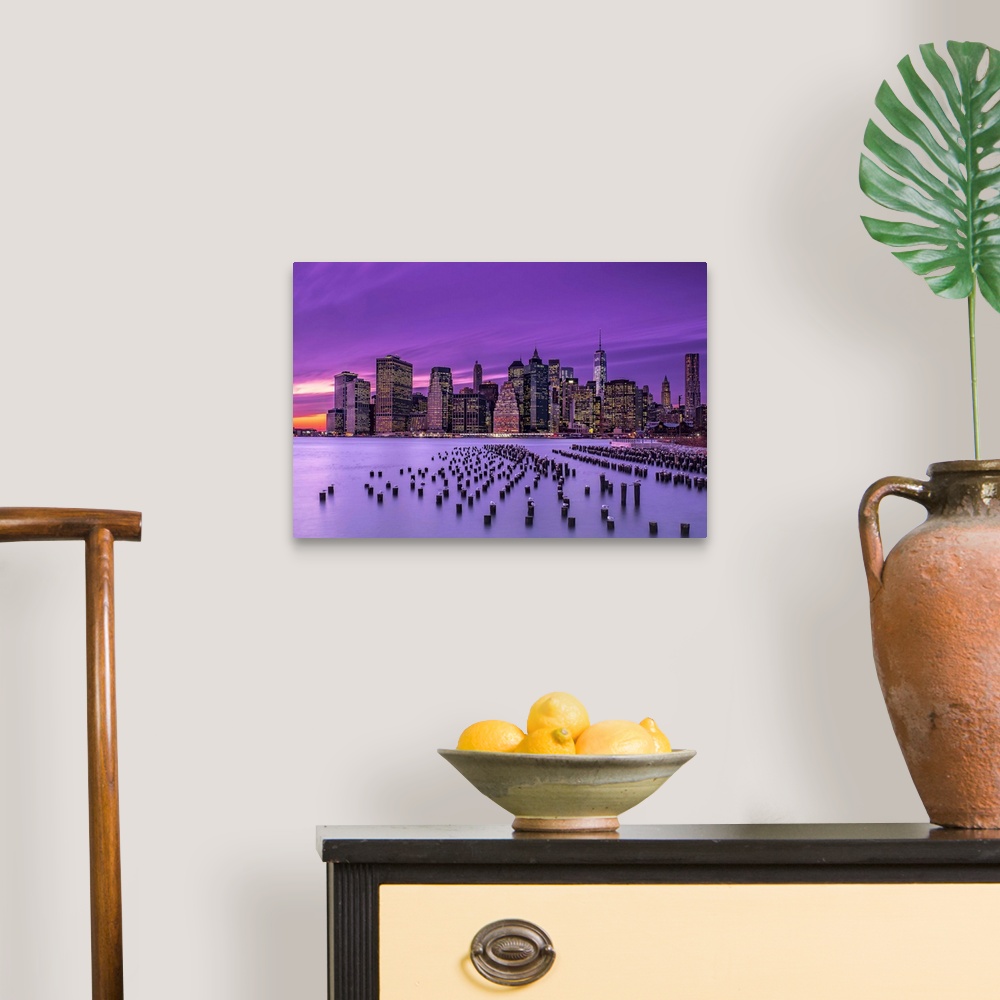 A traditional room featuring Manhattan skyline at sunset under a purple sky, seen from Brooklyn.