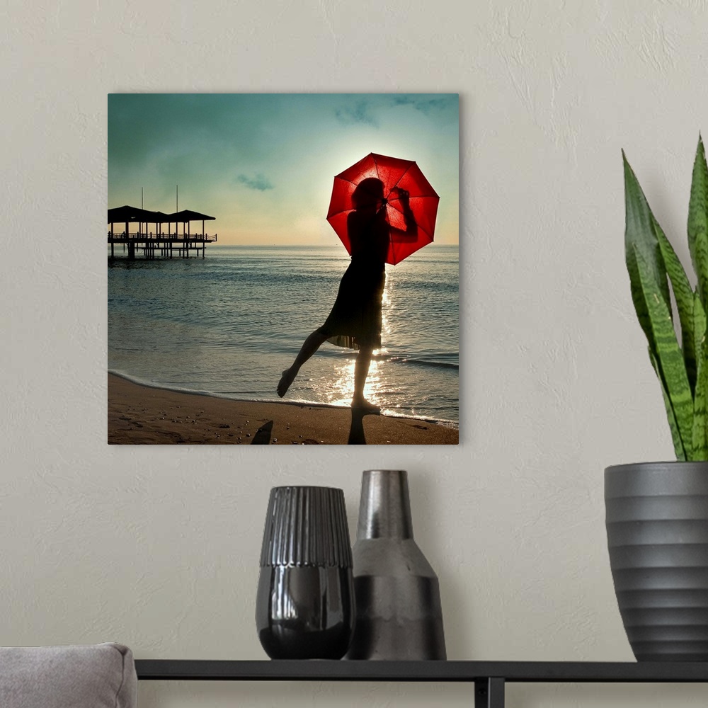 A modern room featuring A woman on the beach seen through a red umbrella, with a pier in the distance.