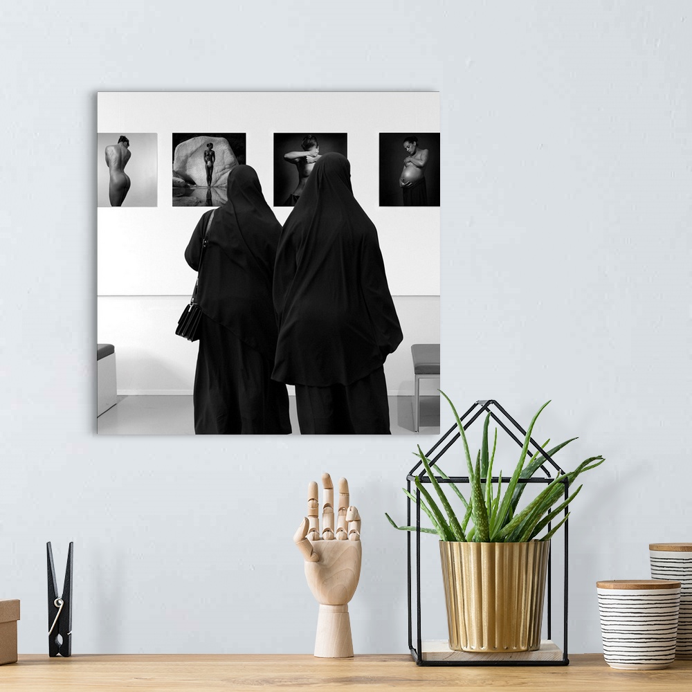 A bohemian room featuring Two women wearing veils looking at fine art in a museum.