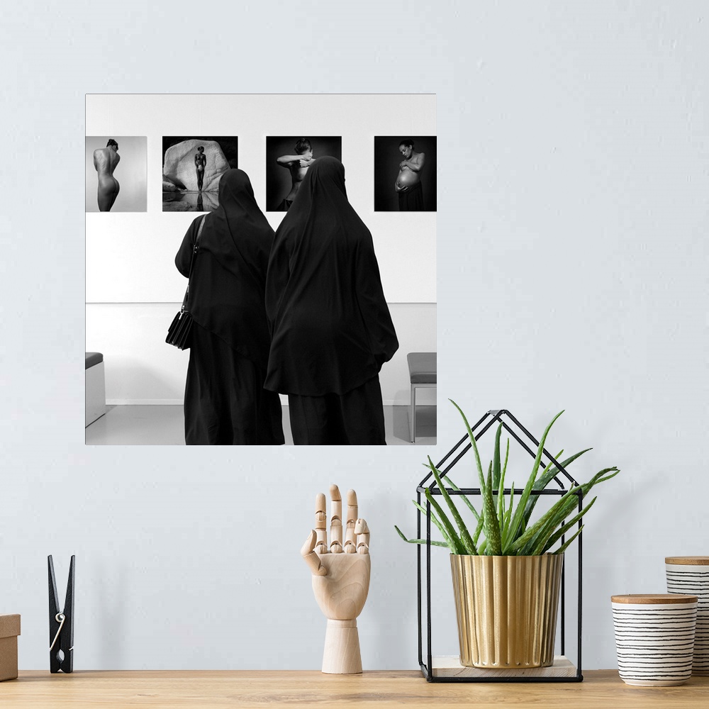 A bohemian room featuring Two women wearing veils looking at fine art in a museum.