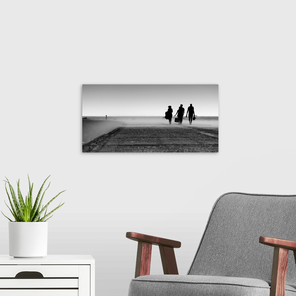 A modern room featuring A black and white photograph of three silhouetted figures walking toward a mist.