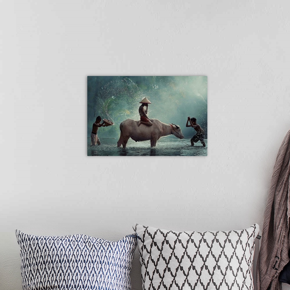 A bohemian room featuring A boy sitting on a cow while other people splash water on them.