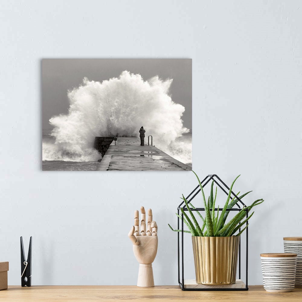 A bohemian room featuring A photographer standing on a pier with waves crashing.