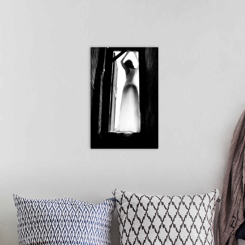 A bohemian room featuring Black and white portrait of a woman standing in a doorway with light shining in.