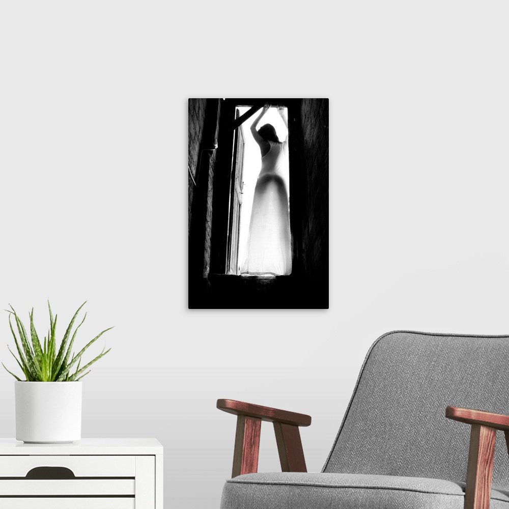 A modern room featuring Black and white portrait of a woman standing in a doorway with light shining in.