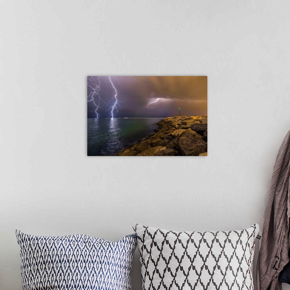 A bohemian room featuring An intense photograph of a coastal scene with multiple lightning strikes hitting the ocean.