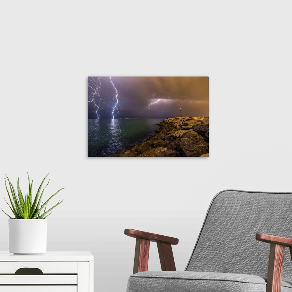 A modern room featuring An intense photograph of a coastal scene with multiple lightning strikes hitting the ocean.