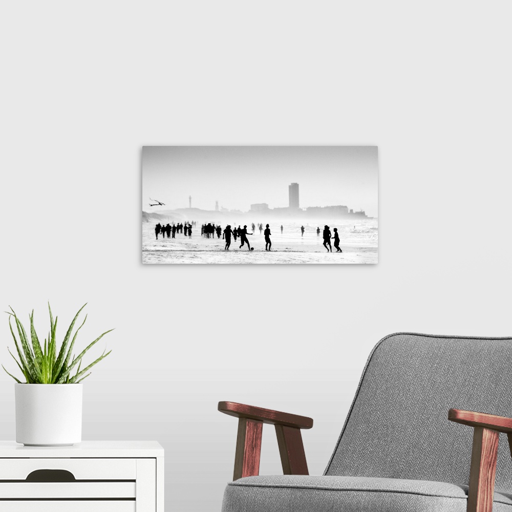 A modern room featuring Soft, horizontal black and white photograph with silhouettes of people walking and playing on the...