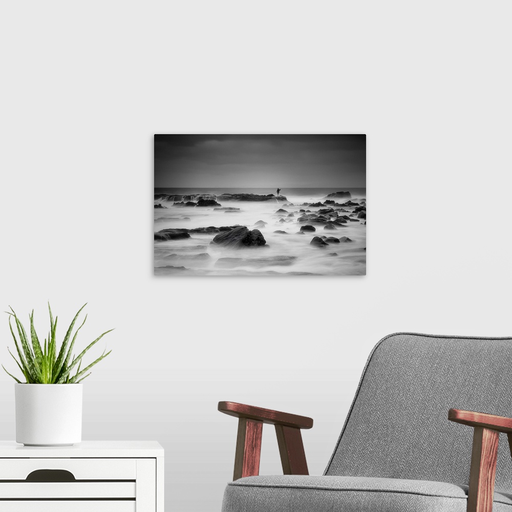 A modern room featuring A figure stands in the distance on a rock protruding from the misty ocean.