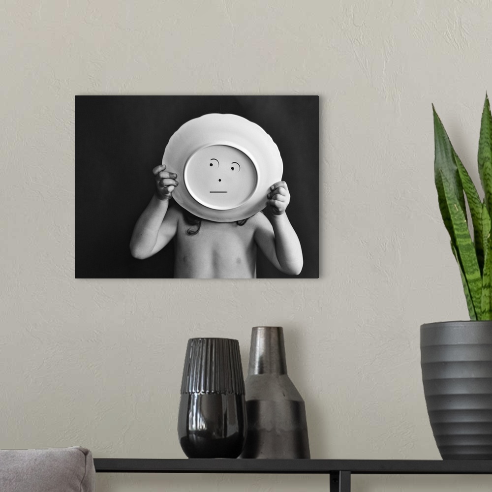 A modern room featuring A child holds up a bowl with a simple face drawn on the bottom.