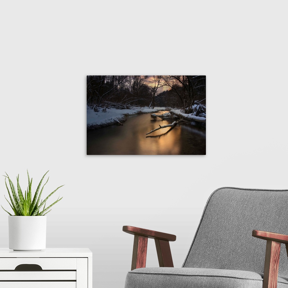A modern room featuring A serene river reflecting evening light in a snowy forest in the winter.