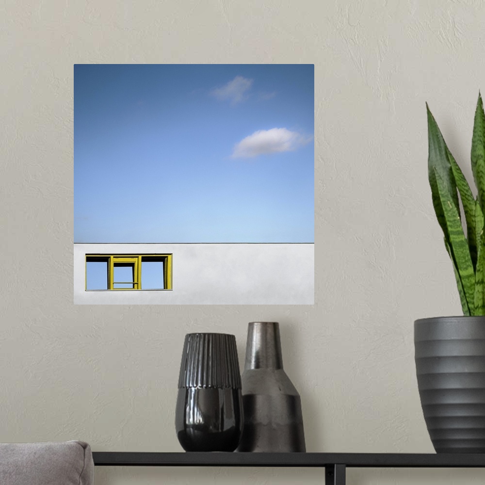 A modern room featuring Abstract view of a yellow framed window on a blank white wall facade, under a blue almost cloudle...