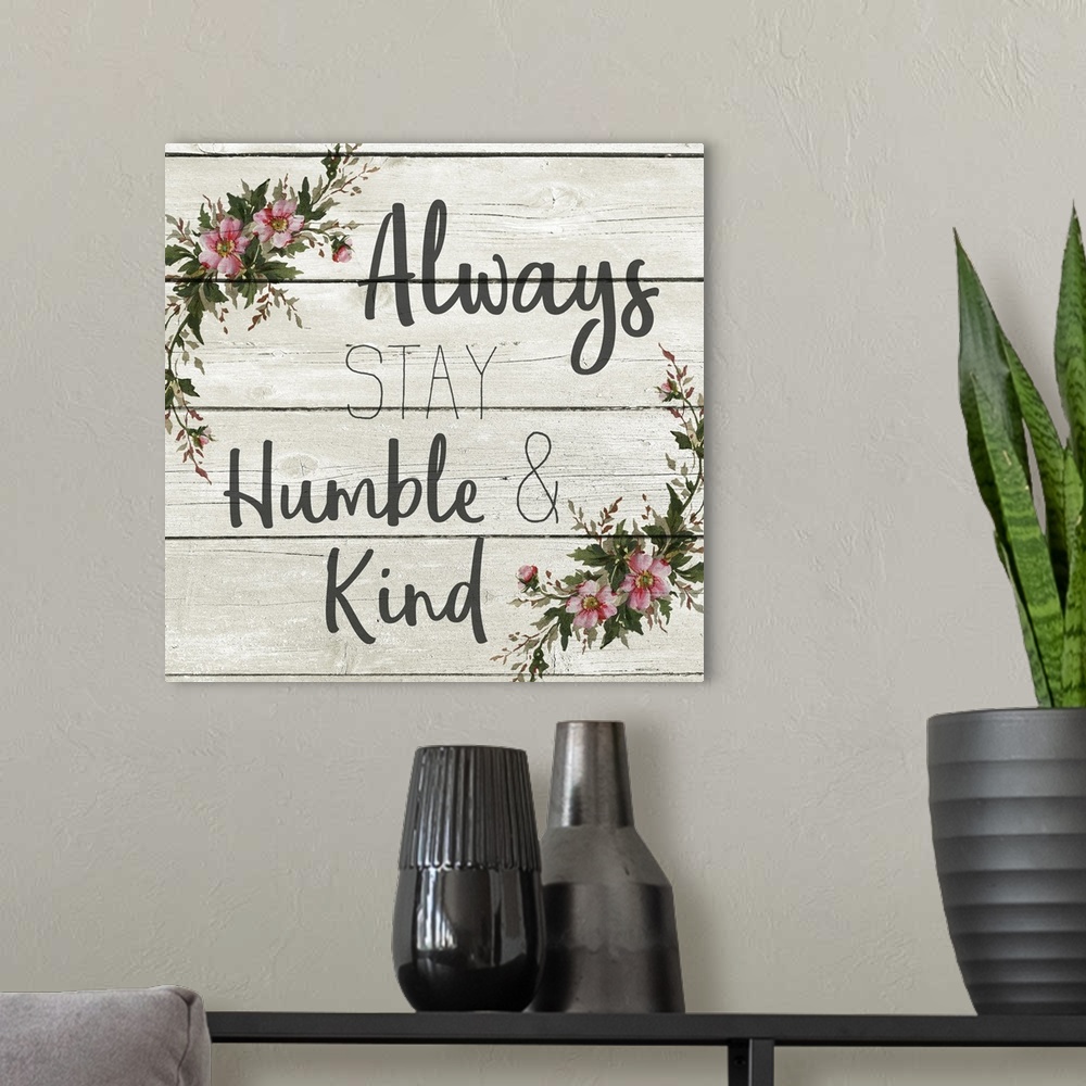 A modern room featuring "Always Stay Humble and Kind" with a wreath of flowers on a gray wood plank background.