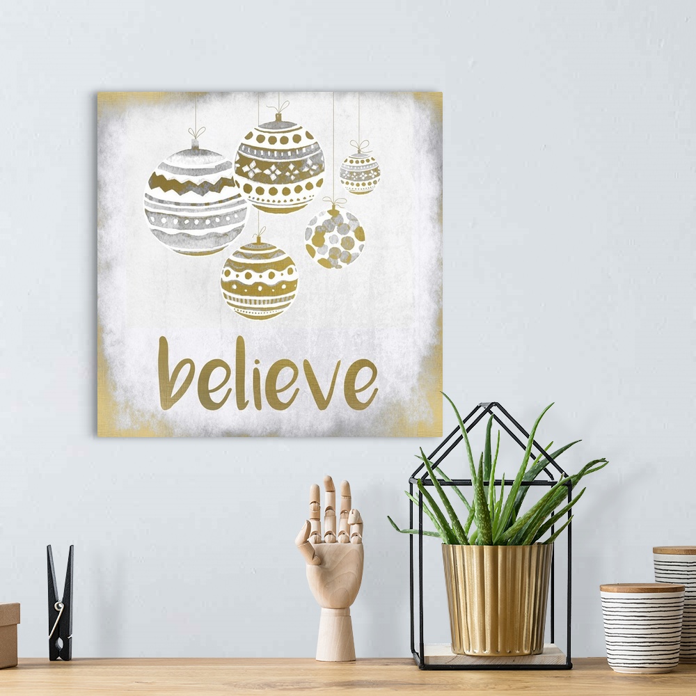 A bohemian room featuring Gold and silver holiday ornaments hanging over the word "Believe."