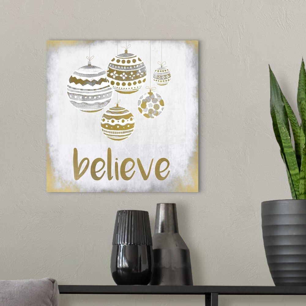 A modern room featuring Gold and silver holiday ornaments hanging over the word "Believe."