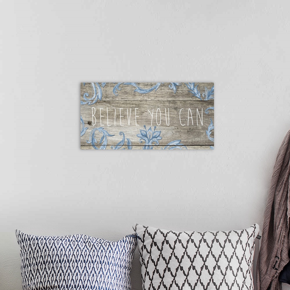 A bohemian room featuring "Believe you can" in thin letters on a wooden plank with blue florals.