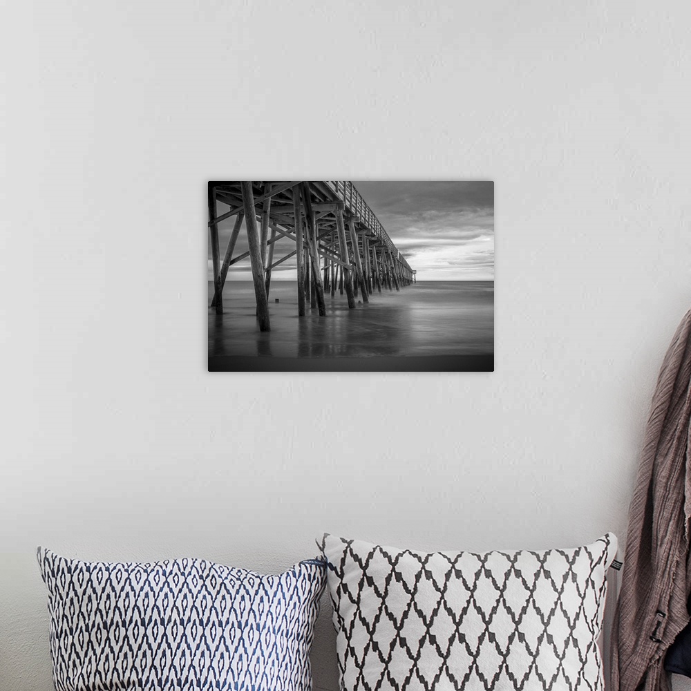 A bohemian room featuring A black and white photograph of a long pier jetting out over the ocean.
