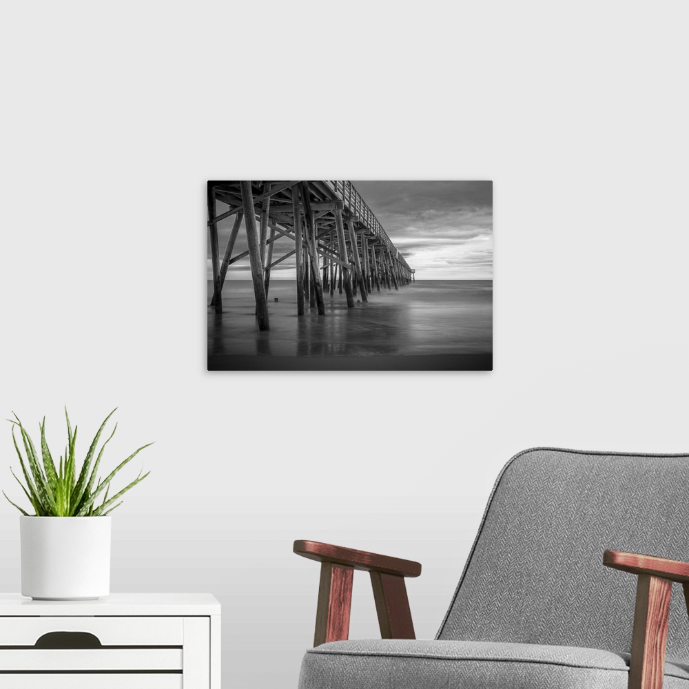 A modern room featuring A black and white photograph of a long pier jetting out over the ocean.
